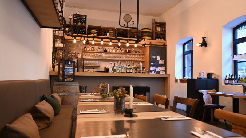 Gemütliches Restaurant mit Bar, Holztischen und -stühlen, dekorativen Elementen und warmem Licht. Die Bar ist gut bestückt mit Flaschen und Gläsern. Gemütliches Restaurant mit Bar, Holztischen und -stühlen, dekorativen Elementen und warmem Licht. Die Bar ist gut bestückt mit Flaschen und Gläsern.