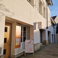 Das Bild zeigt die Au&szlig;enansicht des Caf&eacute; Regenbogen mit einem Schild und einem Aufsteller vor der Eingangst&uuml;r. Die Fassade ist hell und die Stra&szlig;e gepflastert., &copy; cStadtNuertingen