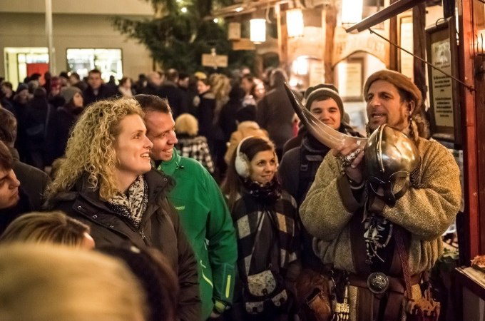 Ein Mann in mittelalterlicher Kleidung zeigt ein Horn auf einem belebten Mittelaltermarkt. Besucher schauen interessiert zu., © Esslinger Stadtmarketing &amp; Tourismus GmbH