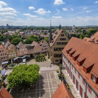 Panoramablick auf Bietigheim-Bissingen mit Fachwerkhäusern, roten Ziegeldächern und einem zentralen Platz, umgeben von grüner Landschaft und blauem Himmel., © SMG, Achim Mende Panoramablick auf Bietigheim-Bissingen mit Fachwerkhäusern, roten Ziegeldächern und einem zentralen Platz, umgeben von grüner Landschaft und blauem Himmel., © SMG, Achim Mende