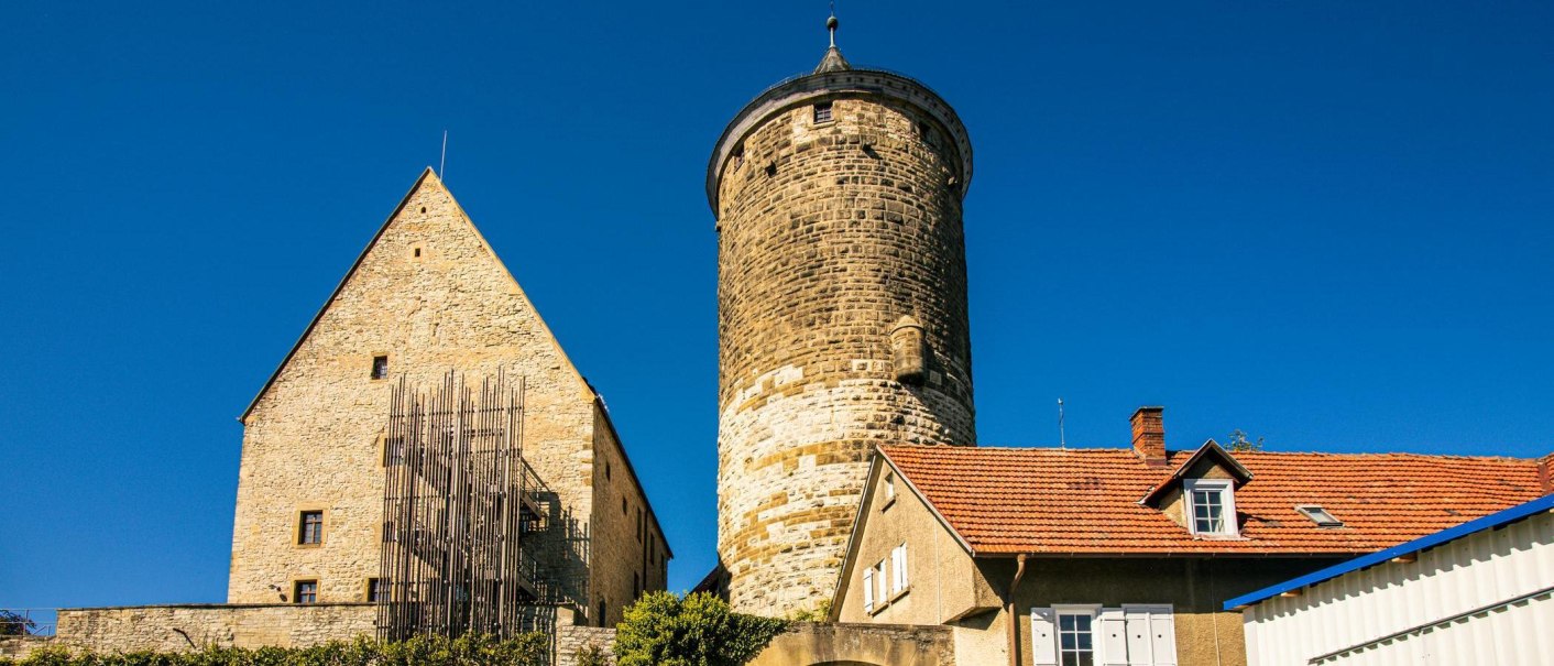 Ein historisches Gebäudeensemble in Besigheim mit einem markanten Turm und einem Haus mit rotem Ziegeldach unter klarem, blauem Himmel., © Stuttgart-Marketing GmbH, Sarah Schmid