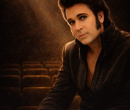 Ein Mann in einem leeren Theater, gekleidet wie Elvis Presley, sitzt nachdenklich unter einem Scheinwerferlicht., &copy; Touristik Bad Wildbad GmbH