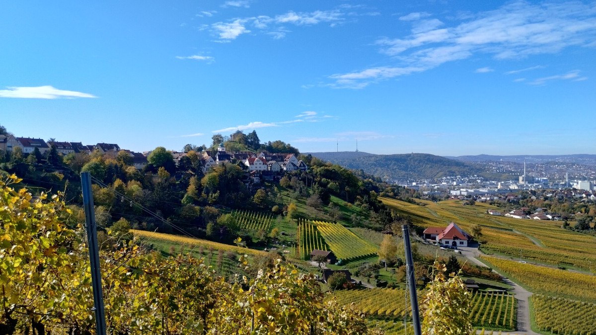 Hügelige Landschaft mit Weinbergen, einer Siedlung auf einem Hügel und einem klaren blauen Himmel im Hintergrund. Hügelige Landschaft mit Weinbergen, einer Siedlung auf einem Hügel und einem klaren blauen Himmel im Hintergrund.
