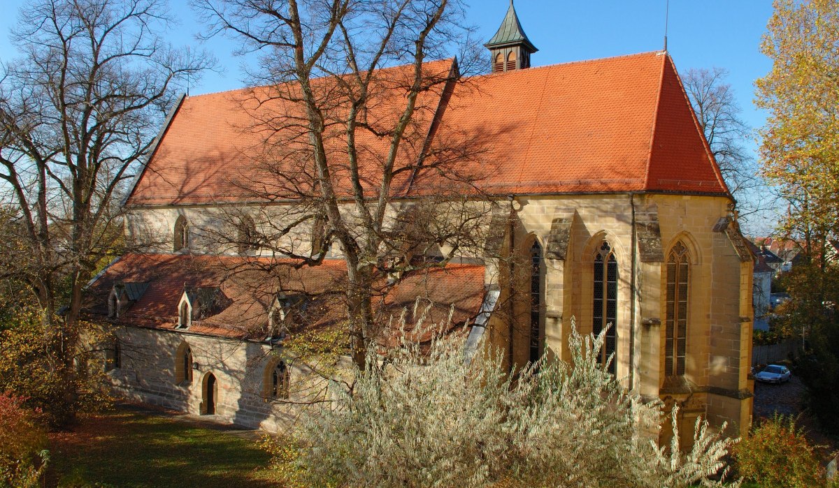 Die Schlosskirche in Winnenden mit rotem Ziegeldach und gotischen Fenstern, umgeben von herbstlichen Bäumen unter blauem Himmel., © SWT