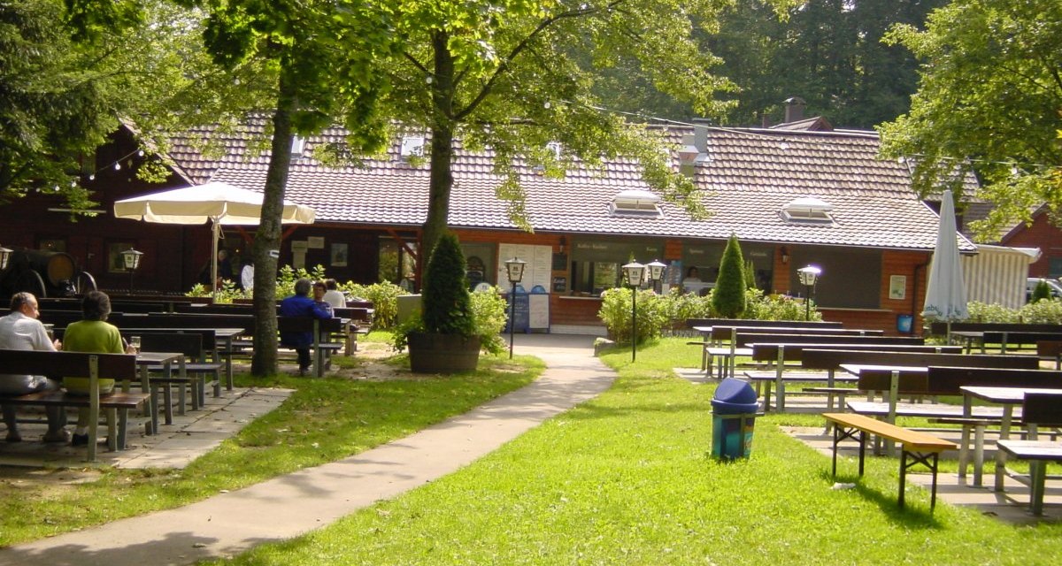Ein Biergarten mit Holzb&auml;nken und Tischen im Freien, umgeben von B&auml;umen. Im Hintergrund ein Geb&auml;ude mit Ziegeldach., &copy; Naturpark Sch&ouml;nbuch