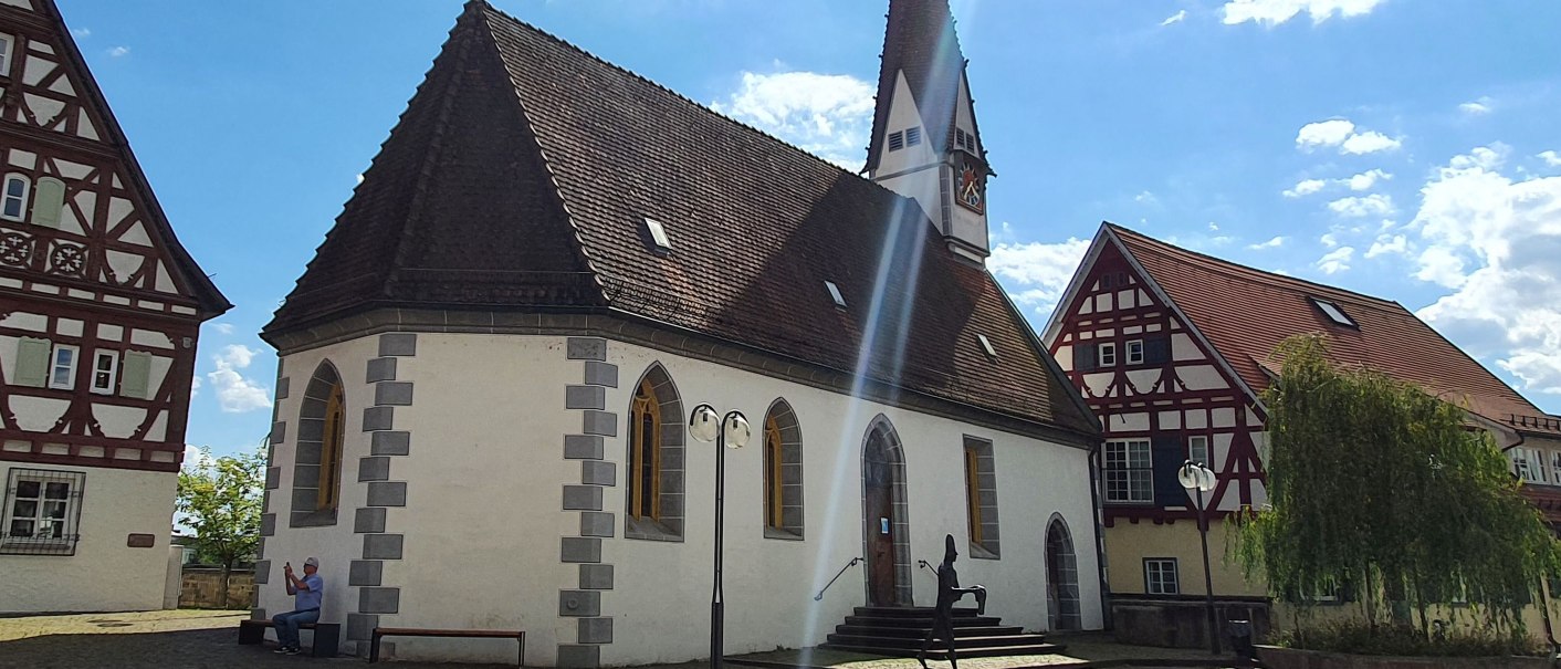 Die Ottilienkapelle mit spitzem Turm und Fachwerkhäusern im Hintergrund, bei sonnigem Wetter und blauem Himmel., © PlochingenInfo