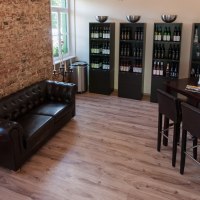 Gemütliche Vinothek mit Ledersofa, Weinregalen und Stehtisch. Ziegelwand und Kerzenständer verleihen dem Raum eine elegante Atmosphäre., © Weingut Zaißerei