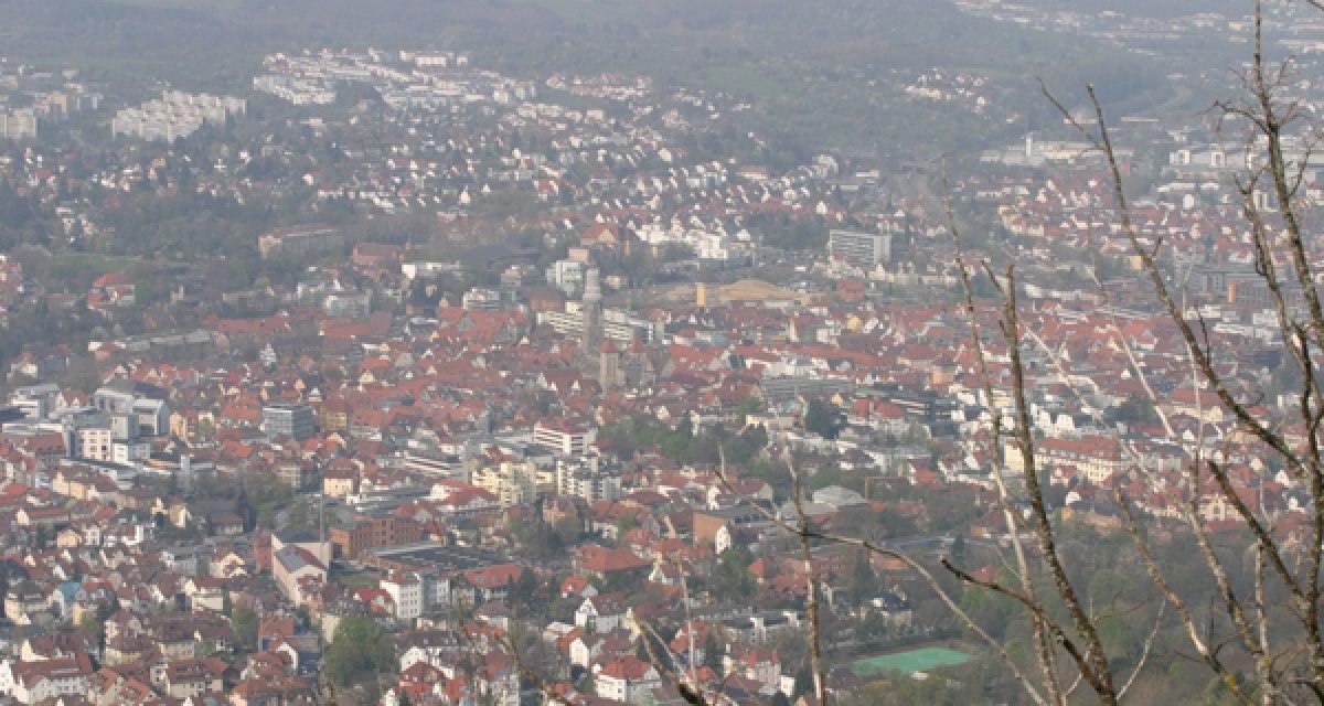 Panoramablick auf eine Stadt mit roten Dächern, umgeben von grünen Hügeln und Bäumen im Vordergrund., © Mythos Schwäbische Alb im Landkreis Reutlingen e.V. Panoramablick auf eine Stadt mit roten Dächern, umgeben von grünen Hügeln und Bäumen im Vordergrund., © Mythos Schwäbische Alb im Landkreis Reutlingen e.V.