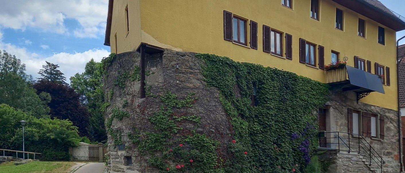 Stadtmauer und ehemaliger Wachturm in der Grabenstra&szlig;e - Gelbes Haus an der Stra&szlig;e. Die Au&szlig;enwand des Erdgeschoss ist die alte Stadtmauer. Sie besteht aus gro&szlig;en gemauerten Steinen und ist mit Efeu bewachsen. Der Himmel ist leicht bew&ouml;lkt., &copy; Petra Natzkowski