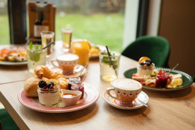 Ein Frühstückstisch mit Croissants, Joghurt, Marmelade, Kaffee und Saft. Im Hintergrund sind weitere Teller und Getränke zu sehen., © Ingrid Glückswelt