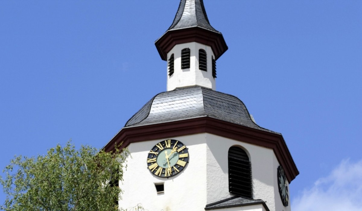 Ein Kirchturm mit Uhr und Wetterhahn ragt in den blauen Himmel. Ein Baum und ein Ziegeldach sind im Vordergrund sichtbar., © Natur.Nah. Schönbuch & Heckengäu Ein Kirchturm mit Uhr und Wetterhahn ragt in den blauen Himmel. Ein Baum und ein Ziegeldach sind im Vordergrund sichtbar., © Natur.Nah. Schönbuch & Heckengäu