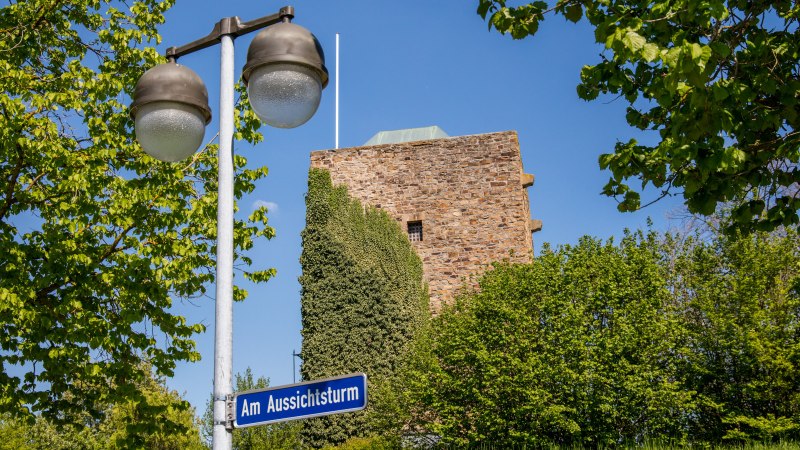 Der Aussichtsturm des Schwäbischen Albvereins in Plochingen ist hinter grünen Bäumen und einer Straßenlaterne zu sehen., © SMG, Achim Mende