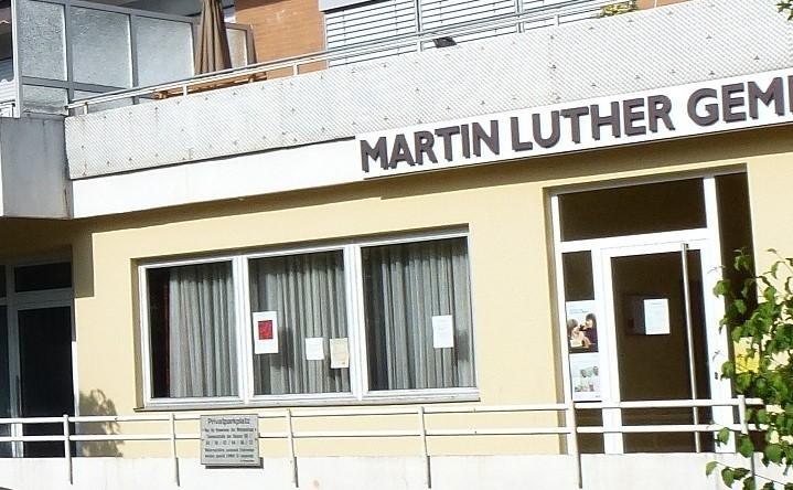 Eingang der Martin Luther Gemeinde mit großen Fenstern und einem Schild über der Tür. Ein Geländer verläuft entlang der Fassade., © Böblingen