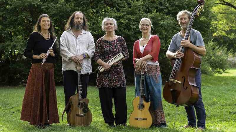 Fünf Personen stehen auf einer Wiese mit Instrumenten: Flöte, Gitarre, Melodica, Gitarre und Kontrabass. Im Hintergrund sind Bäume zu sehen., © Kulturhaus Schwanen Fünf Personen stehen auf einer Wiese mit Instrumenten: Flöte, Gitarre, Melodica, Gitarre und Kontrabass. Im Hintergrund sind Bäume zu sehen., © Kulturhaus Schwanen