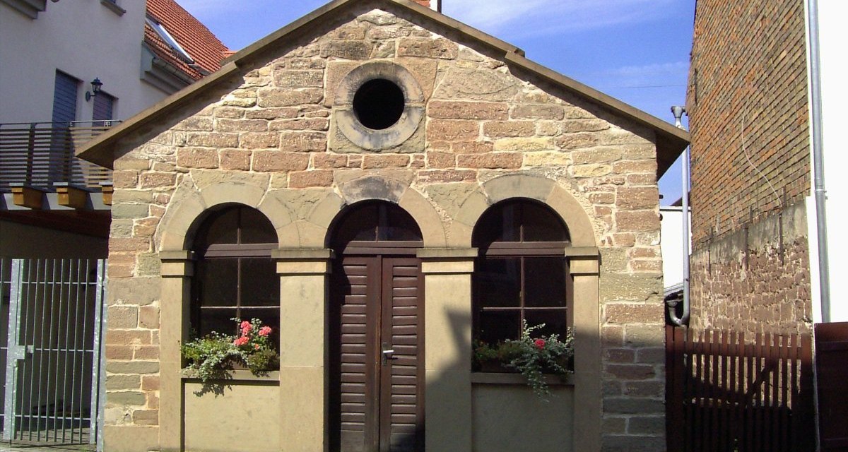 Historisches Backhaus aus Sandstein mit Rundbogenfenstern, Blumen in den Fensterkästen, umgeben von modernen Gebäuden., © Land der 1000 Hügel - Kraichgau-Stromberg Historisches Backhaus aus Sandstein mit Rundbogenfenstern, Blumen in den Fensterkästen, umgeben von modernen Gebäuden., © Land der 1000 Hügel - Kraichgau-Stromberg