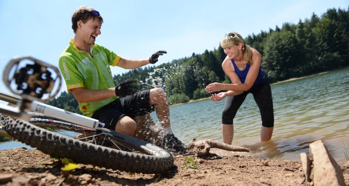 Zwei Personen am Ufer eines Sees, spielen lachend mit Wasser. Ein Fahrrad liegt im Vordergrund auf dem Boden., © Landratsamt Göppingen Zwei Personen am Ufer eines Sees, spielen lachend mit Wasser. Ein Fahrrad liegt im Vordergrund auf dem Boden., © Landratsamt Göppingen