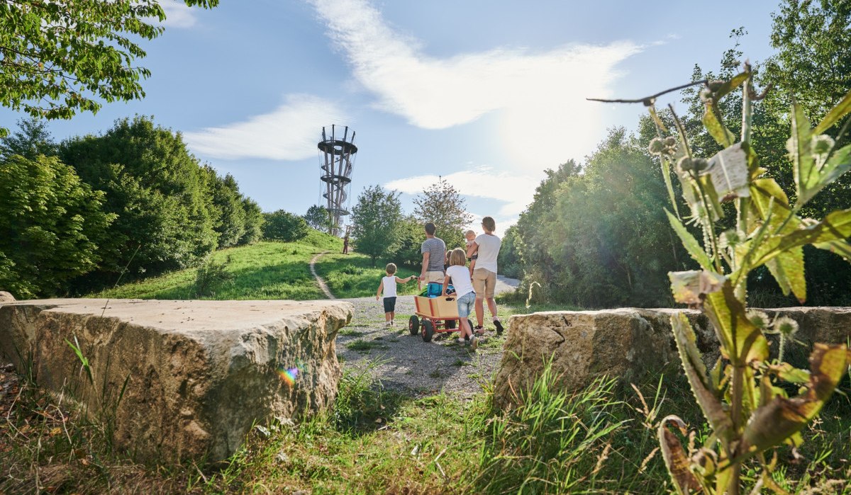 Familie mit Bollerwagen auf einem Weg zu einem Aussichtsturm auf einem grünen Hügel bei Sonnenschein., © Natur.Nah. Schönbuch & Heckengäu Familie mit Bollerwagen auf einem Weg zu einem Aussichtsturm auf einem grünen Hügel bei Sonnenschein., © Natur.Nah. Schönbuch & Heckengäu