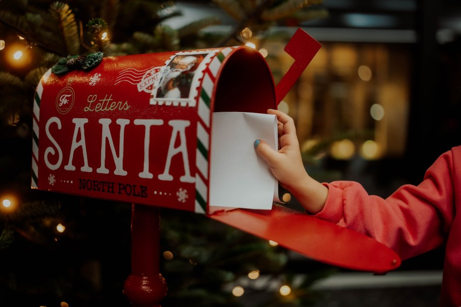 Ein roter Briefkasten mit der Aufschrift 'Letters to Santa' und eine Kinderhand, die einen Brief einwirft., © Nik Ebert