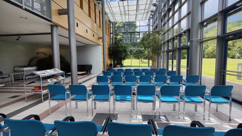 Ein leerer Konferenzraum mit blauen Stühlen, großen Fenstern und viel Tageslicht. Ein Tisch mit Broschüren steht bereit., © Bad Urach Tourismus Ein leerer Konferenzraum mit blauen Stühlen, großen Fenstern und viel Tageslicht. Ein Tisch mit Broschüren steht bereit., © Bad Urach Tourismus