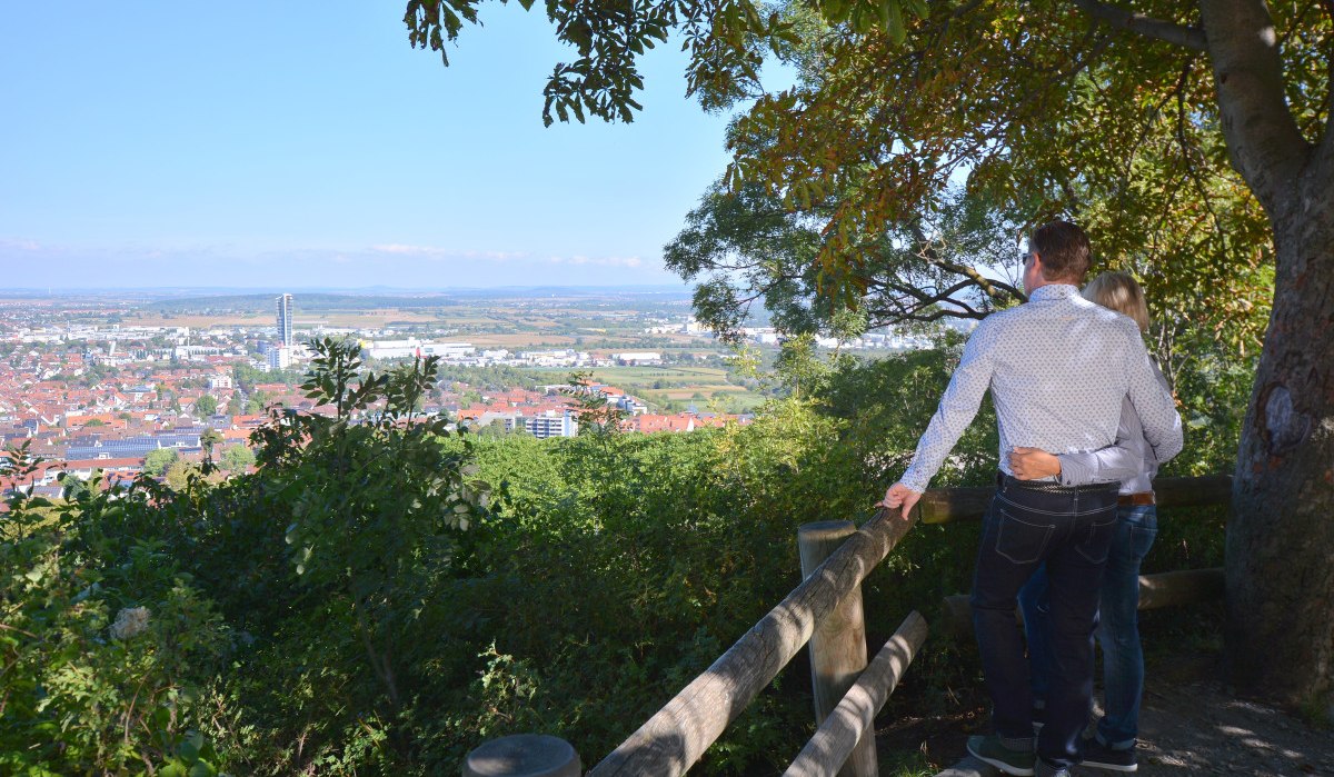 Ein Paar steht an einem Geländer und schaut auf das Remstal. Im Hintergrund ist eine Stadt mit einem hohen Gebäude zu sehen, umgeben von Bäumen., © Remstal Tourismus e.V. Ein Paar steht an einem Geländer und schaut auf das Remstal. Im Hintergrund ist eine Stadt mit einem hohen Gebäude zu sehen, umgeben von Bäumen., © Remstal Tourismus e.V.