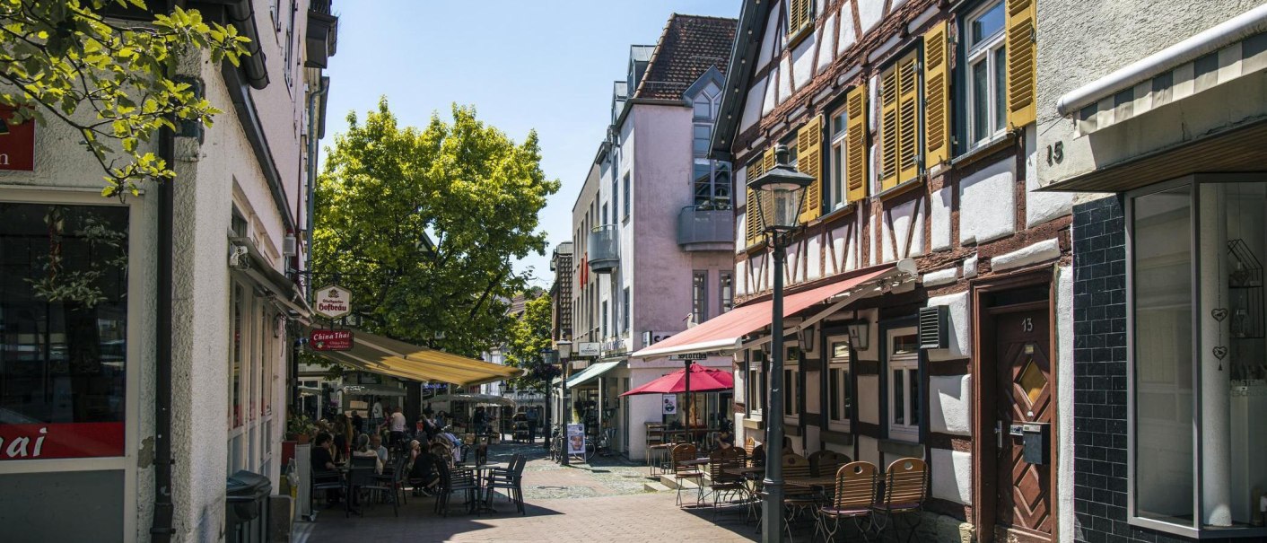 Backnang Altstadt: Fachwerkhäuser, Cafés und Sonnenschirme in einer sonnigen Gasse., © SMG, Sarah Schmid Backnang Altstadt: Fachwerkhäuser, Cafés und Sonnenschirme in einer sonnigen Gasse., © SMG, Sarah Schmid