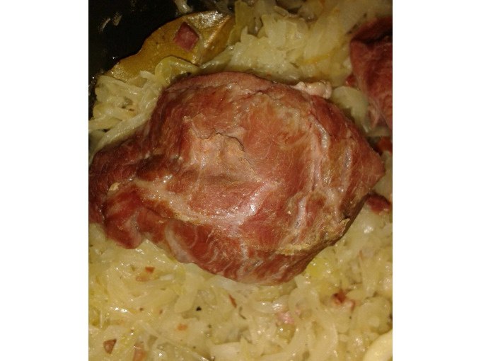Ein St&uuml;ck Fleisch liegt auf einem Bett aus Sauerkraut. Das Gericht scheint in einem Topf oder einer Pfanne zubereitet zu werden., &copy; Kultweine-Kochwelten-Kunst&uuml;cke - Kochschule Sonja Lenz