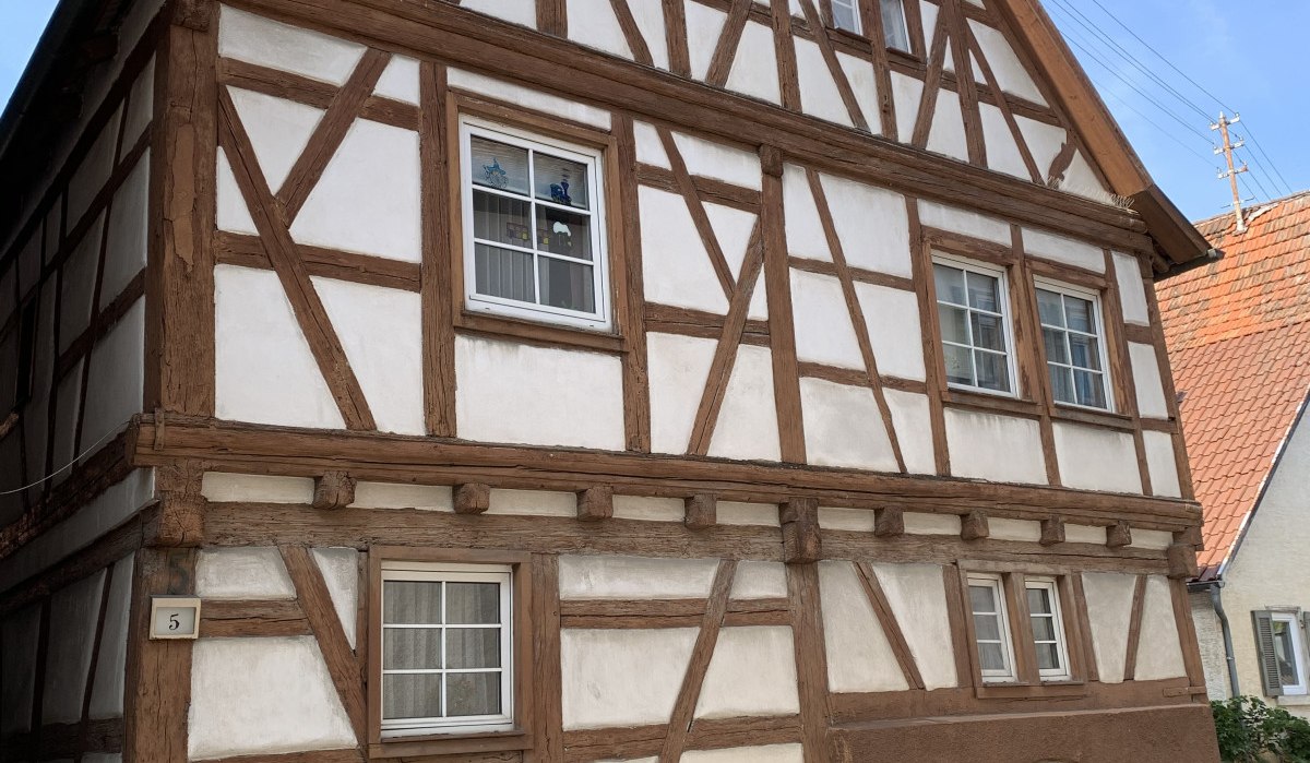 Fachwerkhaus mit braunen Balken und weißem Putz, großes Holztor und mehrere Fenster. Historisches Gebäude unter blauem Himmel., © Land der 1000 Hügel - Kraichgau-Stromberg Fachwerkhaus mit braunen Balken und weißem Putz, großes Holztor und mehrere Fenster. Historisches Gebäude unter blauem Himmel., © Land der 1000 Hügel - Kraichgau-Stromberg
