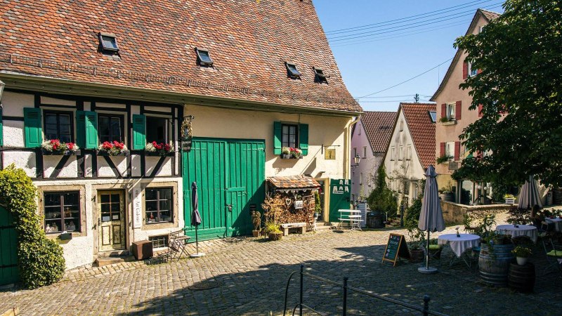 Ein idyllischer Innenhof in N&uuml;rtingens Altstadt mit Fachwerkhaus, gr&uuml;nen Fensterl&auml;den und gem&uuml;tlichen Sitzgelegenheiten unter einem Baum., &copy; Stuttgart-Marketing GmbH, Sarah Schmid