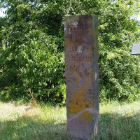 Ein alter Grenzstein mit verwitterter Inschrift steht auf einer Wiese, umgeben von Bäumen und Gras., © Natur.Nah. Schönbuch & Heckengäu Ein alter Grenzstein mit verwitterter Inschrift steht auf einer Wiese, umgeben von Bäumen und Gras., © Natur.Nah. Schönbuch & Heckengäu