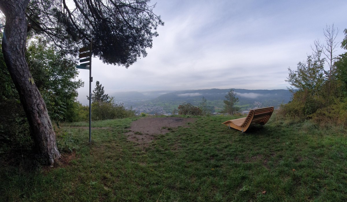 Ein Aussichtspunkt mit einer Holzbank, umgeben von Bäumen, bietet einen weiten Blick auf ein Tal und Hügel im Hintergrund., © Landkreis Göppingen Ein Aussichtspunkt mit einer Holzbank, umgeben von Bäumen, bietet einen weiten Blick auf ein Tal und Hügel im Hintergrund., © Landkreis Göppingen