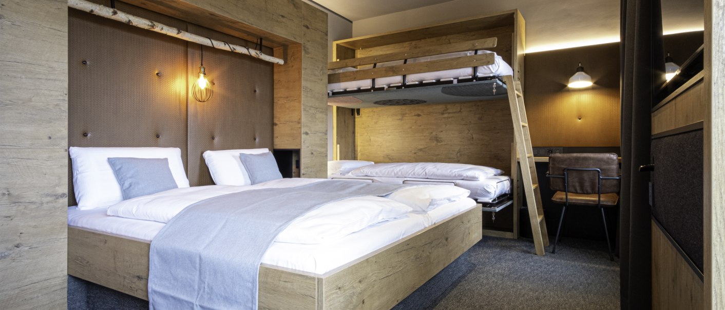 Modernes Familienzimmer mit Doppelbett, Hochbett, Holzverkleidung und stilvoller Beleuchtung. Ein Schreibtisch mit Stuhl ist ebenfalls vorhanden., © 13 6 Design GmbH (Judenhof 10, 89073 Ulm)