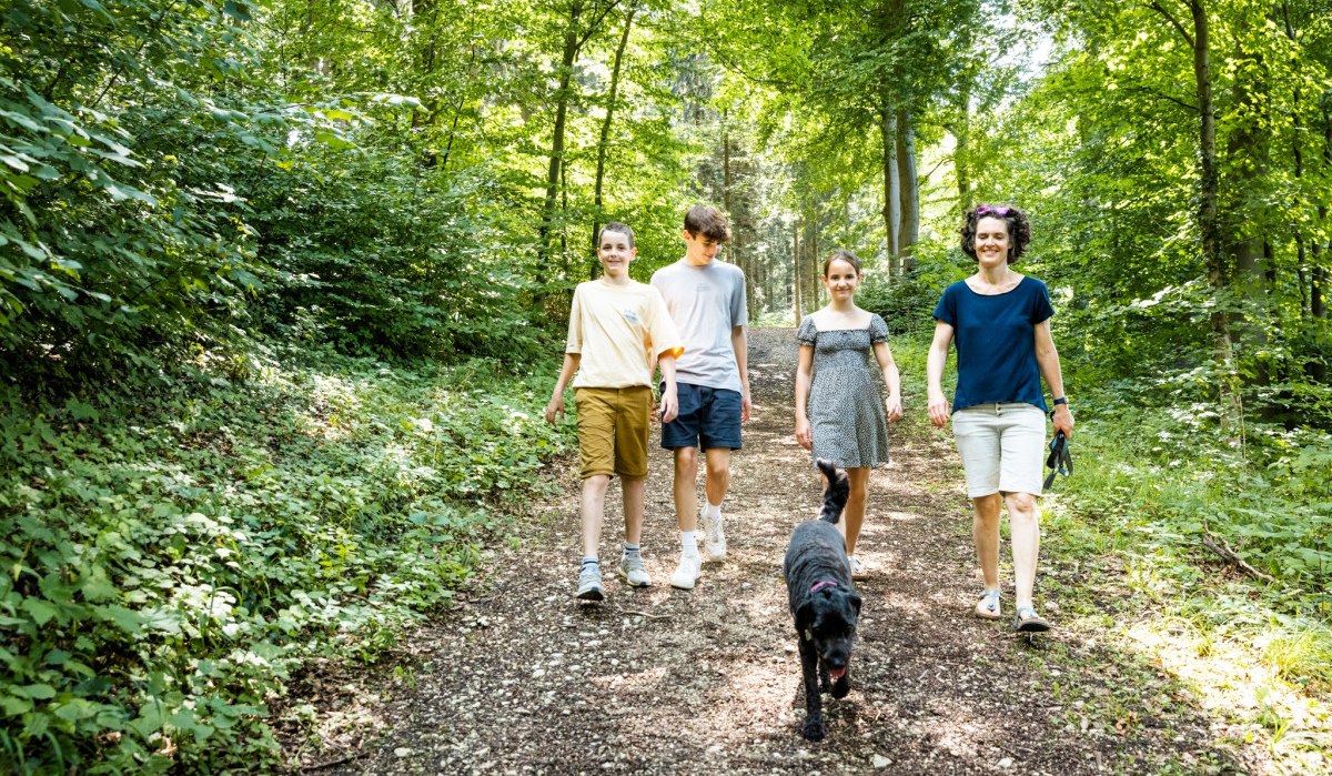 Vier Personen und ein Hund spazieren auf einem Waldweg. Die Umgebung ist grün und sonnig., © Landkreis Göppingen Vier Personen und ein Hund spazieren auf einem Waldweg. Die Umgebung ist grün und sonnig., © Landkreis Göppingen