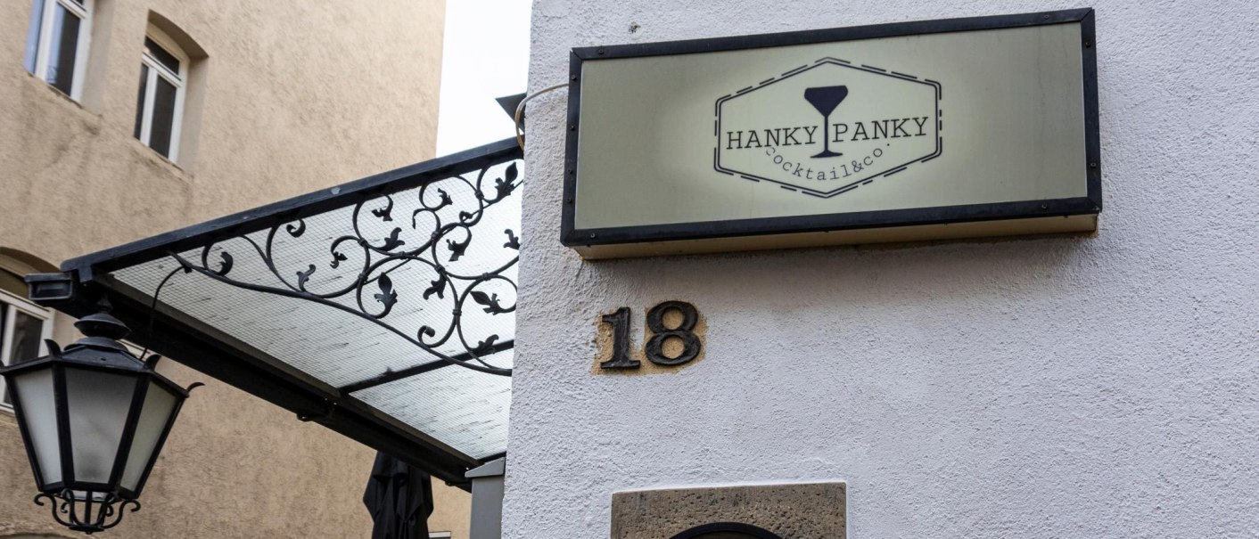 Ein Schild mit der Aufschrift 'Hanky Panky Cocktail & co' h&auml;ngt an einer Hauswand neben der Hausnummer 18. Eine Laterne und ein dekoratives Vordach sind sichtbar., &copy; Stuttgart-Marketing GmbH, Sarah Schmid