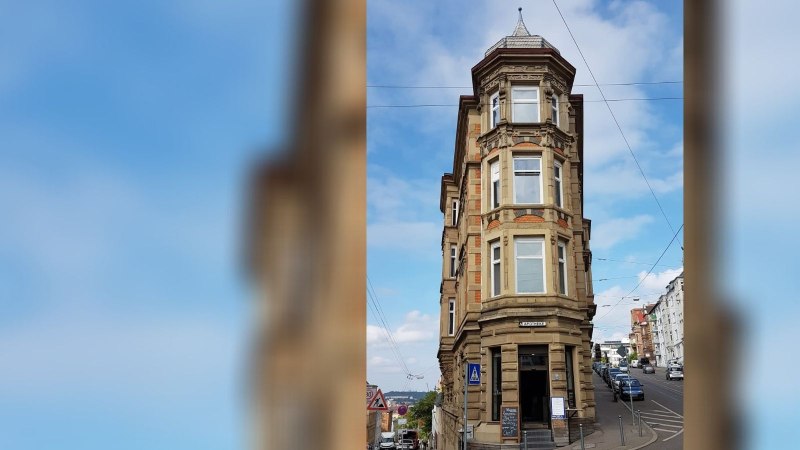 Historisches Eckgebäude mit Apotheke im Erdgeschoss, umgeben von Straßen und Autos, unter blauem Himmel., © SMG