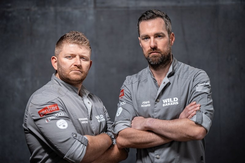 Zwei Männer in grauen Hemden mit "Wild Bakers"-Logo stehen mit verschränkten Armen vor einem grauen Hintergrund., © Stadthalle Leonberg