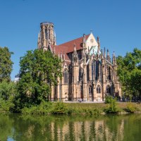 Die Johanneskirche am Feuersee in Stuttgart, umgeben von Bäumen und reflektiert im Wasser, bei klarem, sonnigem Wetter., © SMG Achim Mende Die Johanneskirche am Feuersee in Stuttgart, umgeben von Bäumen und reflektiert im Wasser, bei klarem, sonnigem Wetter., © SMG Achim Mende
