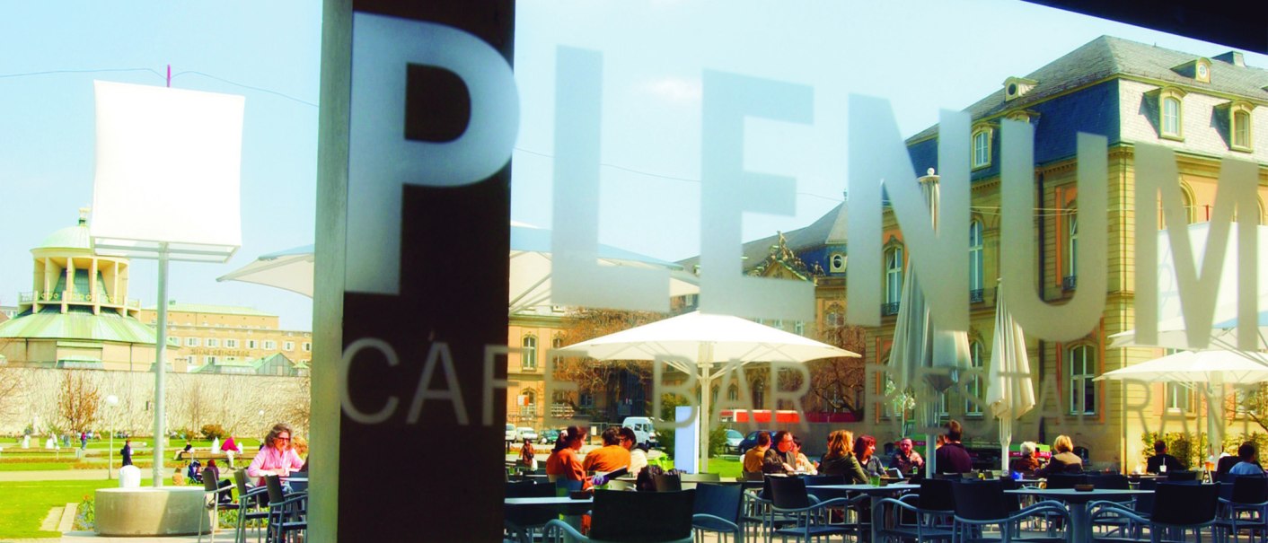 Menschen sitzen im Außenbereich eines Cafés unter Sonnenschirmen. Im Hintergrund sind historische Gebäude zu sehen., © SMG Menschen sitzen im Außenbereich eines Cafés unter Sonnenschirmen. Im Hintergrund sind historische Gebäude zu sehen., © SMG