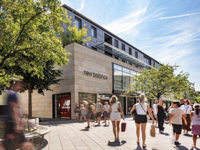 Menschen flanieren vor einem New Balance Gesch&auml;ft in einem modernen Einkaufszentrum bei sonnigem Wetter., &copy; Schlienz-Tours GmbH &amp; Co.KG
