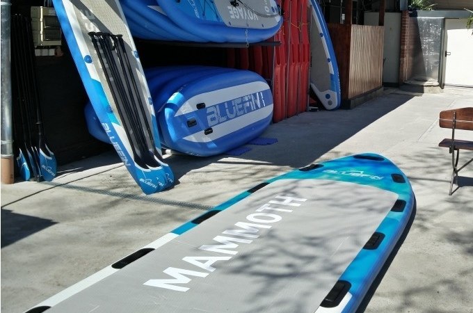 Mehrere Stand Up Paddle Boards in einem Verleih, darunter ein großes Mammut-Board im Vordergrund. Paddel sind an der Seite aufgestellt., © Cool-Tours StattReisen Mehrere Stand Up Paddle Boards in einem Verleih, darunter ein großes Mammut-Board im Vordergrund. Paddel sind an der Seite aufgestellt., © Cool-Tours StattReisen