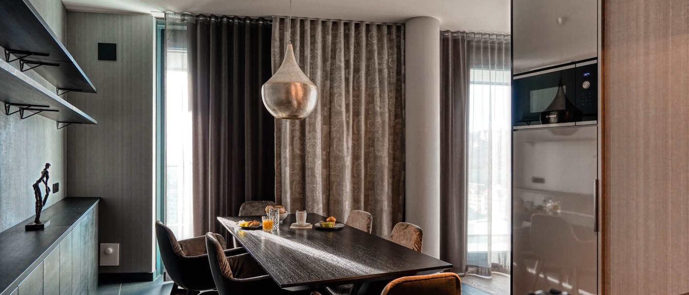Modernes Esszimmer mit großem Tisch, eleganten Stühlen und einer stilvollen Hängelampe in einer Penthouse-Suite., © CLOUD N°7 APARTMENTS GmbH