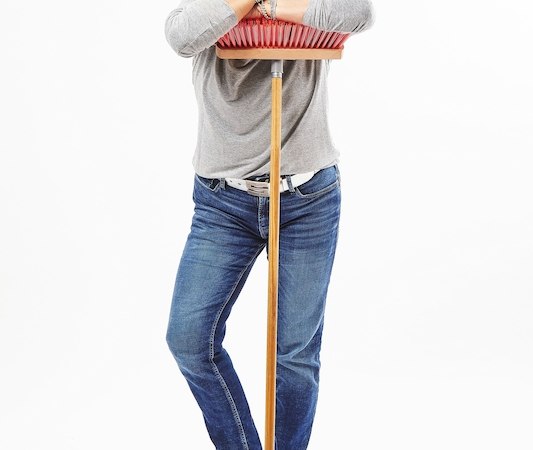 Eine Person lehnt sich lächelnd auf einen roten Besen, trägt ein graues Oberteil, Jeans und weiße Turnschuhe vor weißem Hintergrund., © Interessengemeinschaft Kultur Sindelfingen / Böblingen e.V.