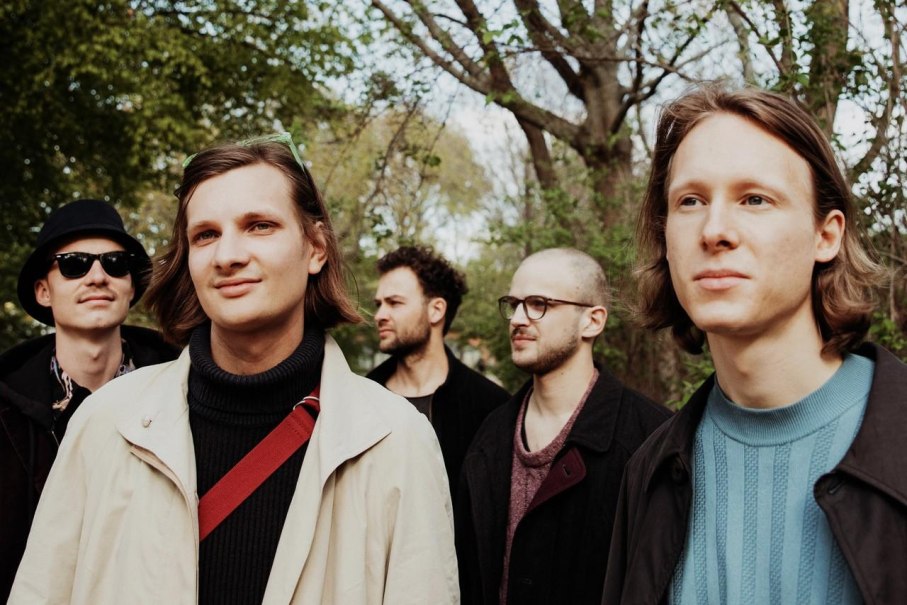 F&uuml;nf junge M&auml;nner stehen in einem Wald und blicken in verschiedene Richtungen. Sie tragen l&auml;ssige Kleidung und wirken entspannt., &copy; Foto kapelle17