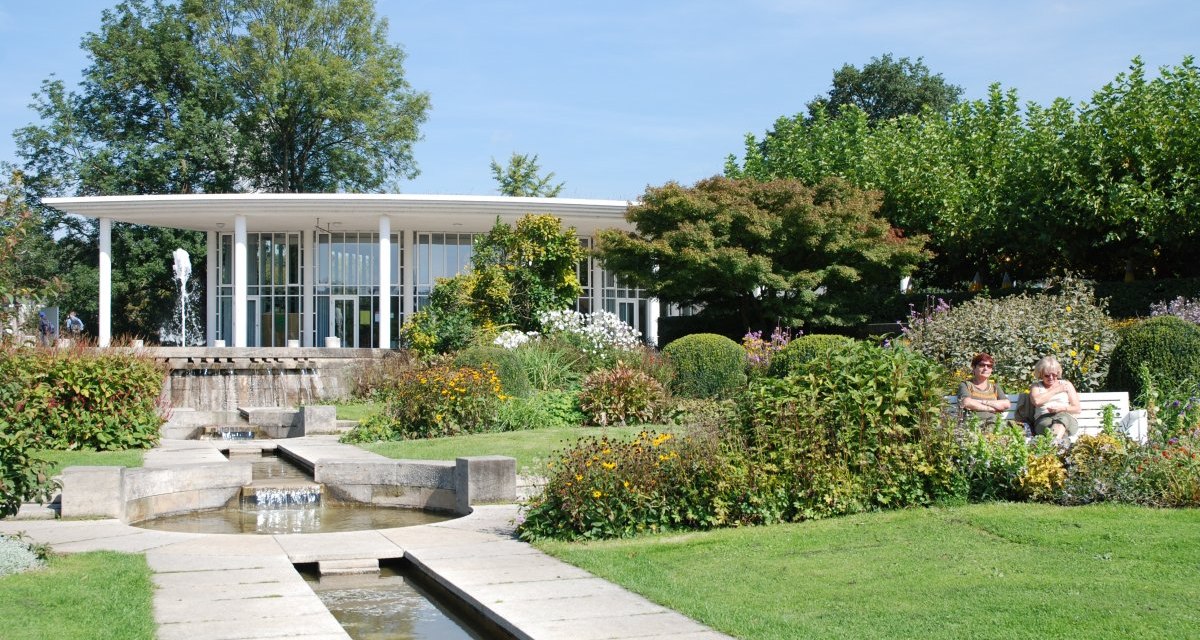 Der Enzpavillon im B&uuml;rgergarten Bietigheim-Bissingen, umgeben von bl&uuml;henden G&auml;rten und einem kleinen Brunnen. Zwei Personen sitzen auf einer Bank., &copy; 3B-Tourismus-Team
