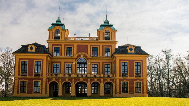 Schloss Favorite in Ludwigsburg, ein barockes Gebäude mit gelben und roten Fassaden, umgeben von Bäumen und Rasen., © Stuttgart-Marketing GmbH, Sarah Schmid