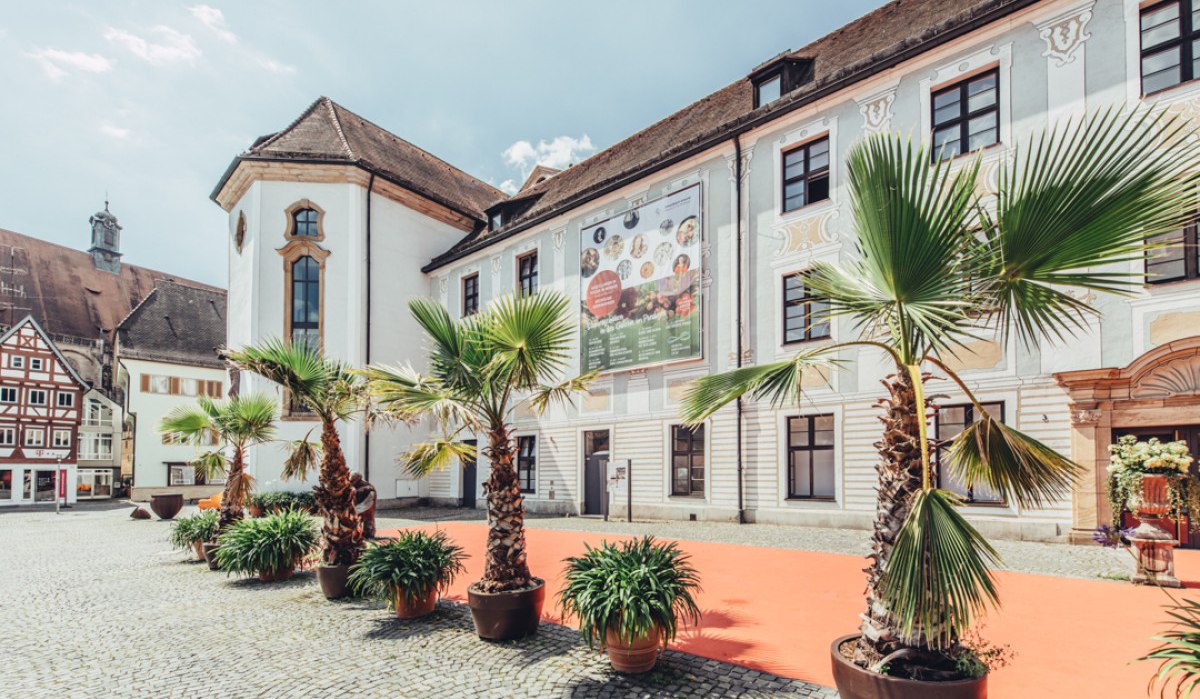 Das Museum im Prediger in Schwäbisch Gmünd, mit Palmen und einem roten Teppich im Vordergrund, bei sonnigem Wetter., © Tourismus Ostalb, Fotograf: Christian Frumolt