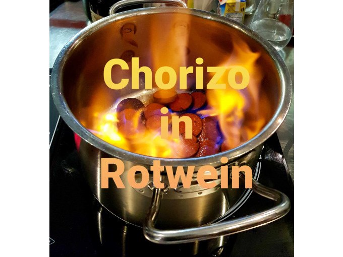 Ein Topf mit Chorizo in Rotwein brennt auf einem Herd. Text: "Chorizo in Rotwein"., © Kultweine-Kochwelten-Kunstücke - Kochschule Sonja Lenz Ein Topf mit Chorizo in Rotwein brennt auf einem Herd. Text: "Chorizo in Rotwein"., © Kultweine-Kochwelten-Kunstücke - Kochschule Sonja Lenz