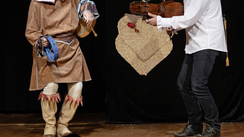 Zwei M&auml;nner auf einer B&uuml;hne, einer tr&auml;gt ein Tierkost&uuml;m mit Tamburin, der andere spielt Geige. Dunkler Hintergrund, Holzboden., &copy; Stadtverwaltung Schorndorf