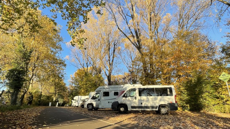 Wohnmobile parken auf einem herbstlichen Stellplatz, umgeben von bunten Bäumen und Laub. Ein Schild weist auf den Wohnmobilstellplatz hin., © Stadtmarketing Göppingen Wohnmobile parken auf einem herbstlichen Stellplatz, umgeben von bunten Bäumen und Laub. Ein Schild weist auf den Wohnmobilstellplatz hin., © Stadtmarketing Göppingen