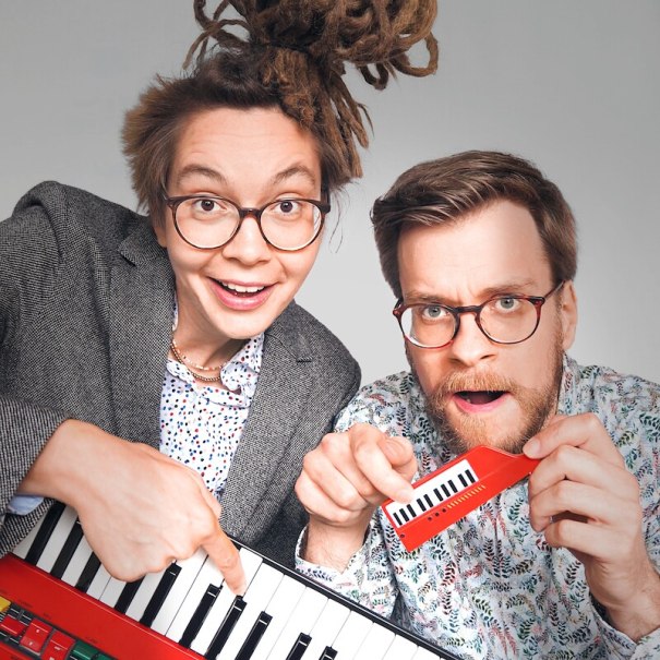 Zwei Personen mit Brillen, eine mit Dreadlocks, halten ein Keyboard und eine kleine Spielzeugtastatur., &copy; Mauerwerk GmbH