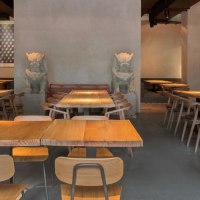 Modernes Restaurant mit Holztischen, Stühlen und asiatischen Dekorationen. Dezente Beleuchtung und kunstvolle Wandgestaltung schaffen eine einladende Atmosphäre., © Breitengrad17, Stuttgart